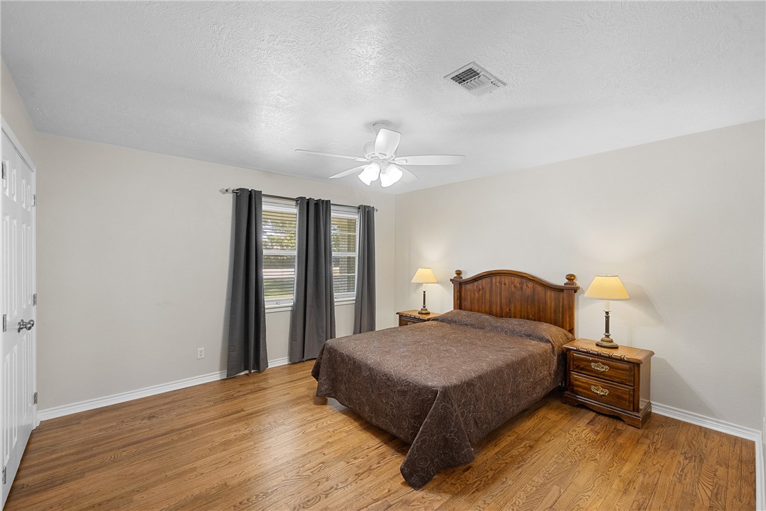 1906 Gun And Rod Road Brenham, TX 77833 - Photo 21 of 30 Bedroom with wood finished floors, a textured ceiling, and a ceiling fan