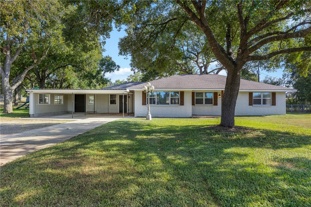 1906 Gun And Rod Road Brenham, TX 77833 - Photo 4 of 30 Ranch-style house featuring driveway, brick siding, a front lawn, and an attached carport