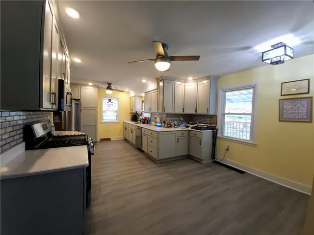 a kitchen with stainless steel appliances kitchen island a sink cabinets and wooden floor