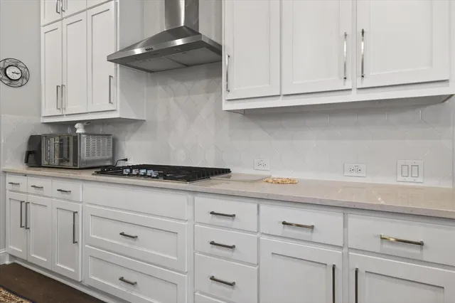 a kitchen with white cabinets and a stove with wooden floor