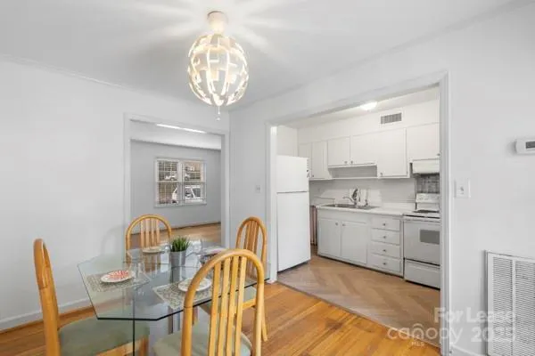 a kitchen with stainless steel appliances granite countertop a stove top oven a sink dishwasher and white cabinets with wooden floor