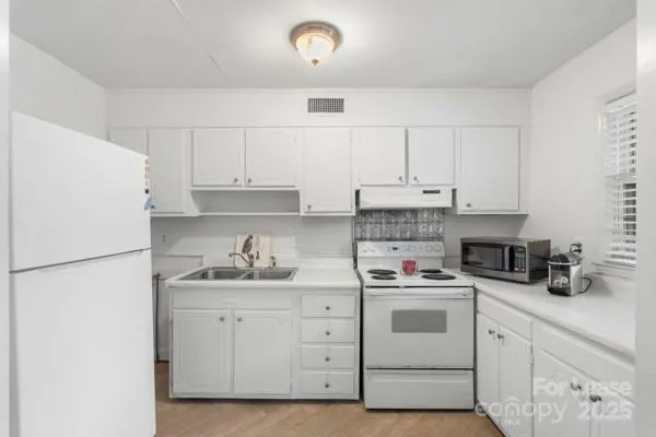 a kitchen with white cabinets and white appliances