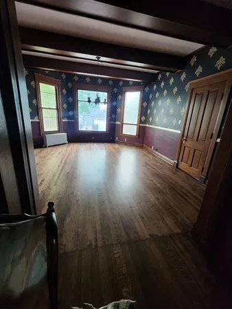 a view of an empty room with wooden floor and windows
