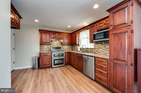 a kitchen with stainless steel appliances granite countertop a refrigerator stove top oven and sink