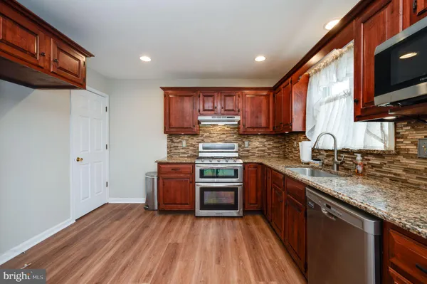 a kitchen with stainless steel appliances granite countertop a stove cabinets and wooden floor