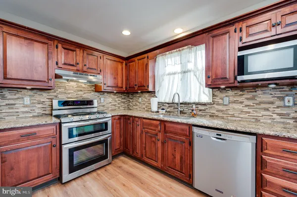 a kitchen with stainless steel appliances granite countertop wooden cabinets and a stove top oven