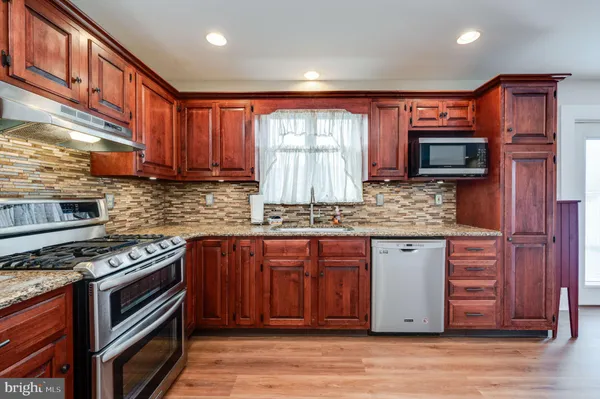 a kitchen with stainless steel appliances granite countertop wooden cabinets a stove a sink and dishwasher