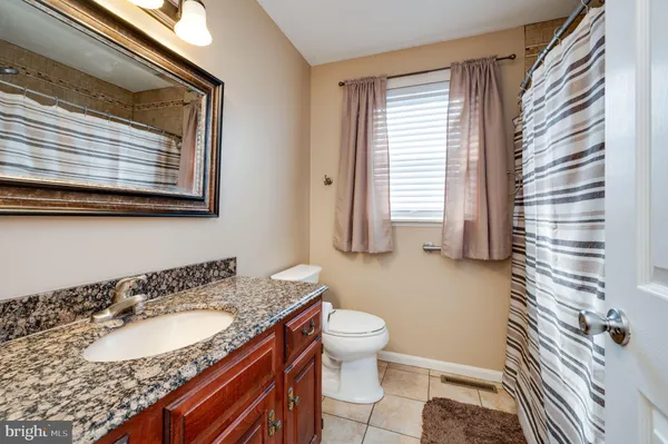 a bathroom with a granite countertop sink toilet and mirror
