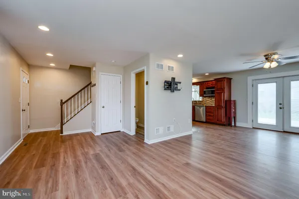 a view of an empty room with wooden floor and a kitchen
