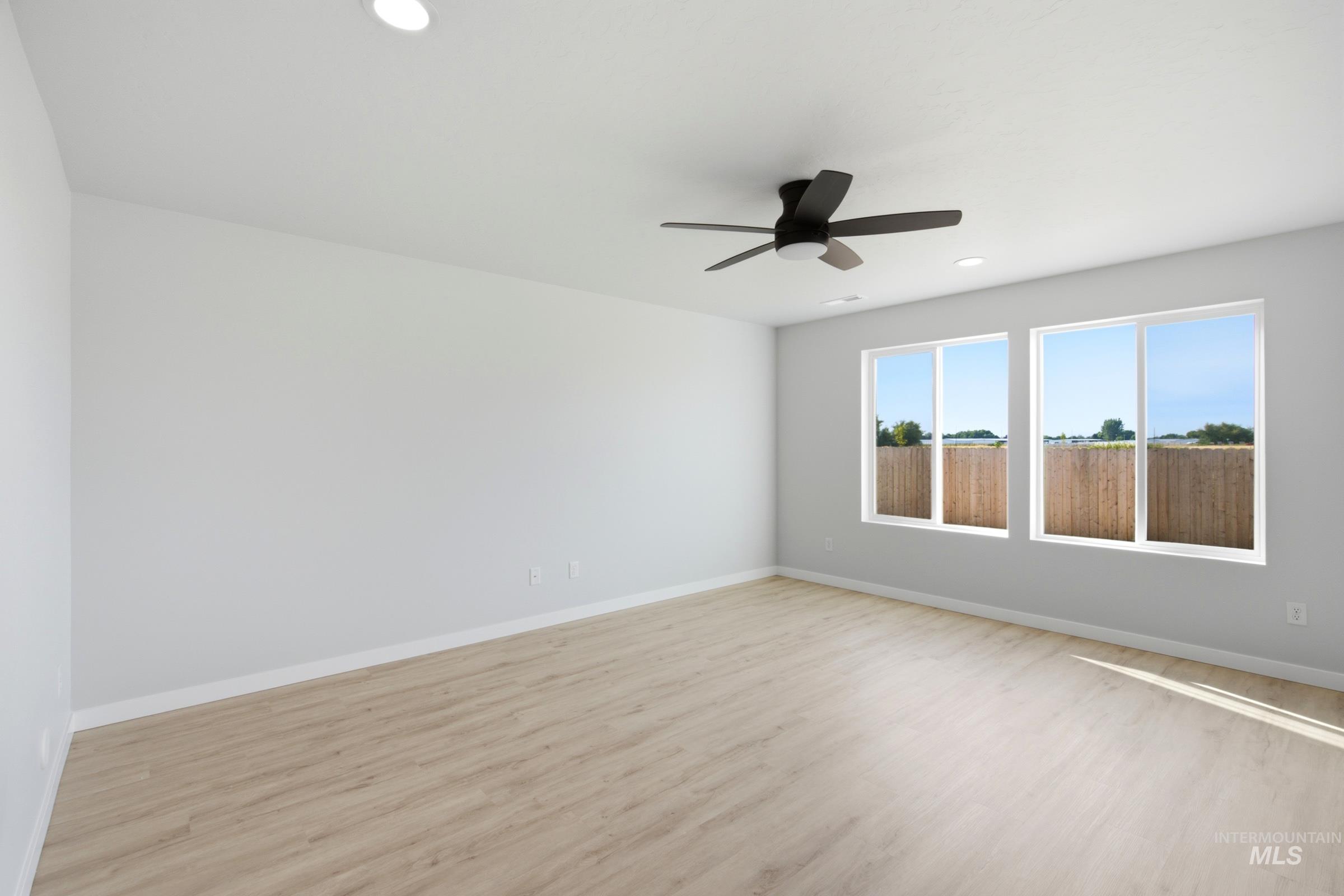 13324 Bank Street Caldwell, ID 83607 - Photo 8 of 29 Recessed ceiling lighting, a modern ceiling fan, two large windows, wood-finish flooring, and white wall finishes