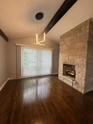 a view of an empty room with wooden floor fireplace and a window