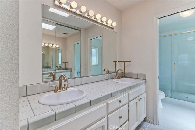 a bathroom with a vanity a sink a mirror and a shower