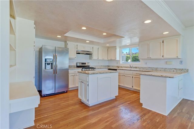 a kitchen with granite countertop a refrigerator and white cabinets