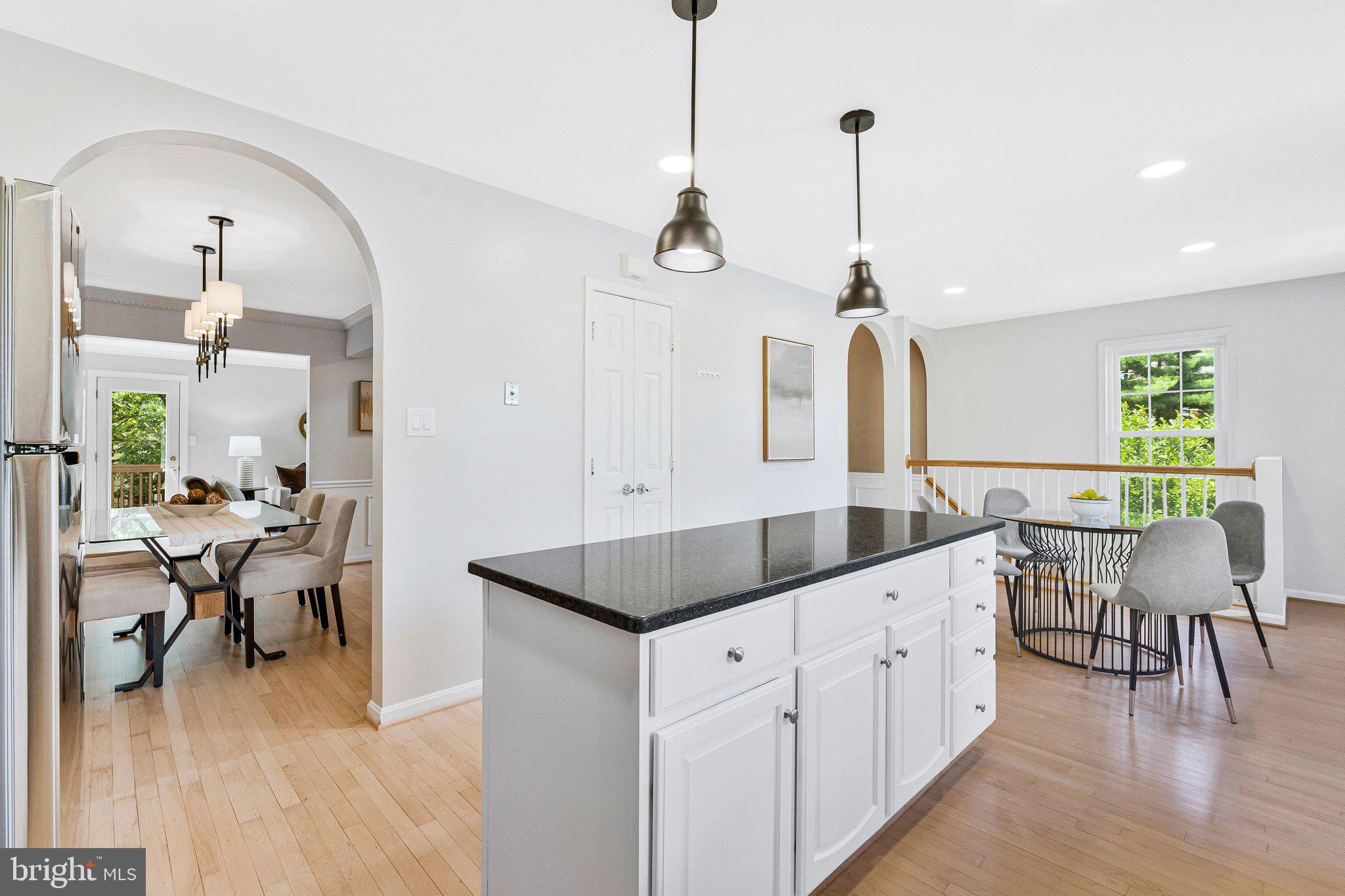 2000 Gallows Tree Lane Vienna, VA 22182 - Photo 14 of 58 a kitchen with stainless steel appliances kitchen island granite countertop a table chairs in it and a wooden floor
