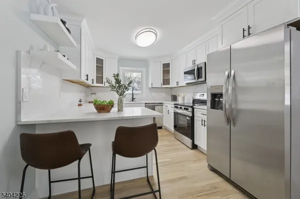 a kitchen with stainless steel appliances a white table chairs and a refrigerator