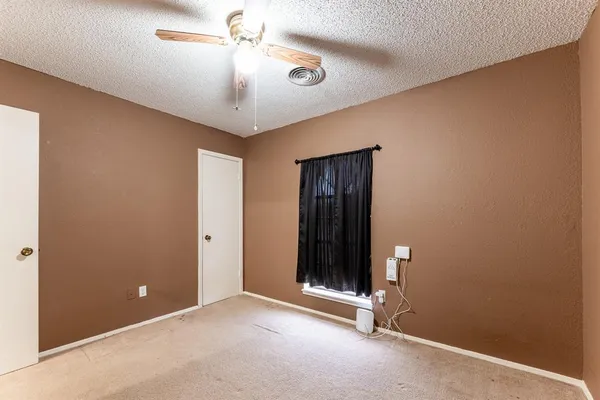 an empty room with closet and a chandelier fan