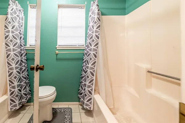 a bathroom with a toilet and shower curtain
