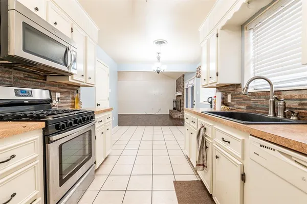 a kitchen with stainless steel appliances a stove a sink and white cabinets