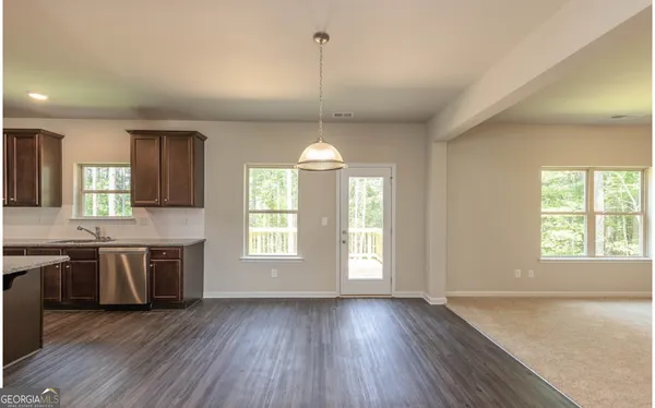 a view of an empty room with window wooden floor and kitchen