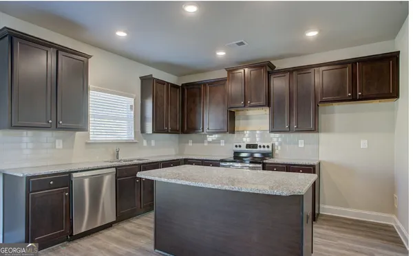 a kitchen with kitchen island granite countertop stainless steel appliances a sink stove and cabinets