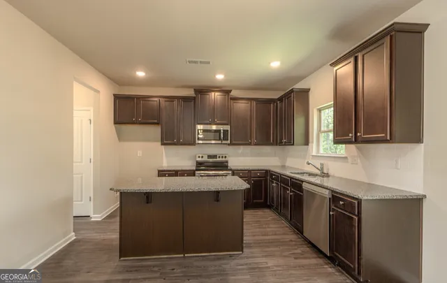 a kitchen with stainless steel appliances granite countertop a sink a stove top oven a refrigerator with grey cabinets