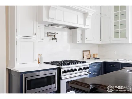 a kitchen with stainless steel appliances granite countertop a stove a sink and a white cabinets
