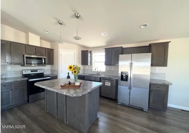 a kitchen with stainless steel appliances granite countertop a refrigerator a stove a sink a microwave and island