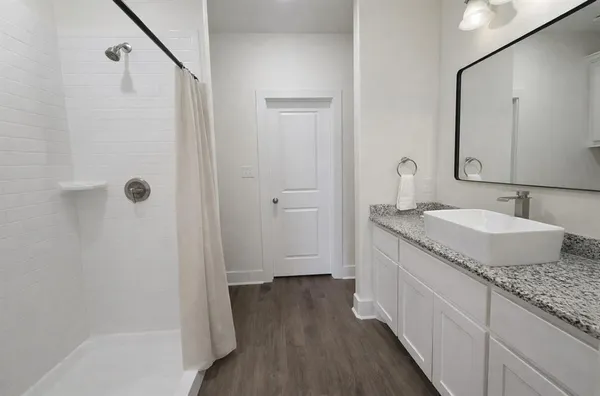 a bathroom with a granite countertop sink a mirror and shower