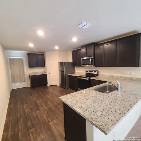 a kitchen with granite countertop a sink and refrigerator