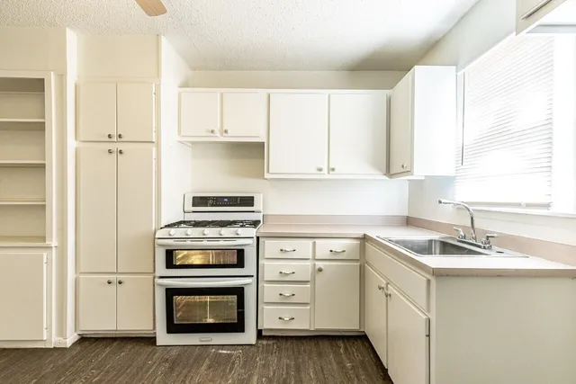 a kitchen with cabinets appliances a sink and a window