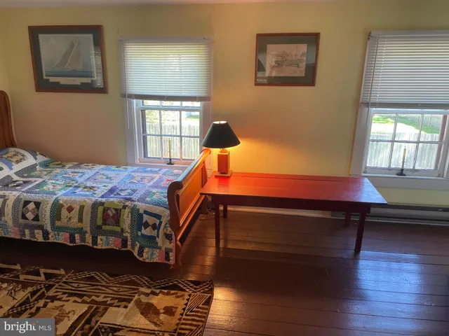 a bedroom with a bed wooden floor and window