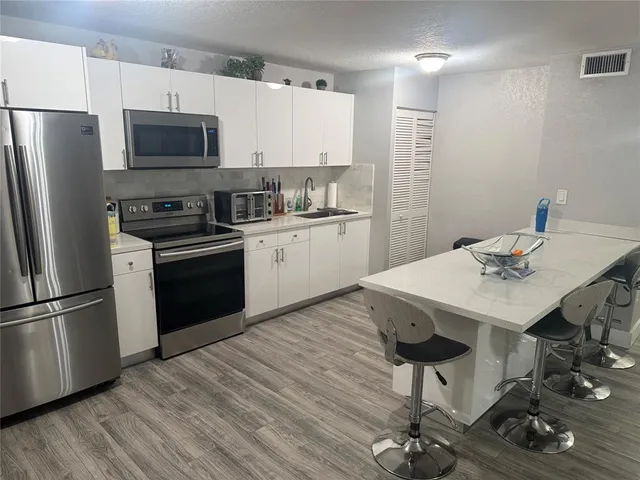 a kitchen with stainless steel appliances a stove a sink refrigerator and microwave