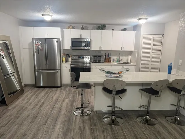 a kitchen with kitchen island stainless steel appliances a sink cabinets and wooden floor