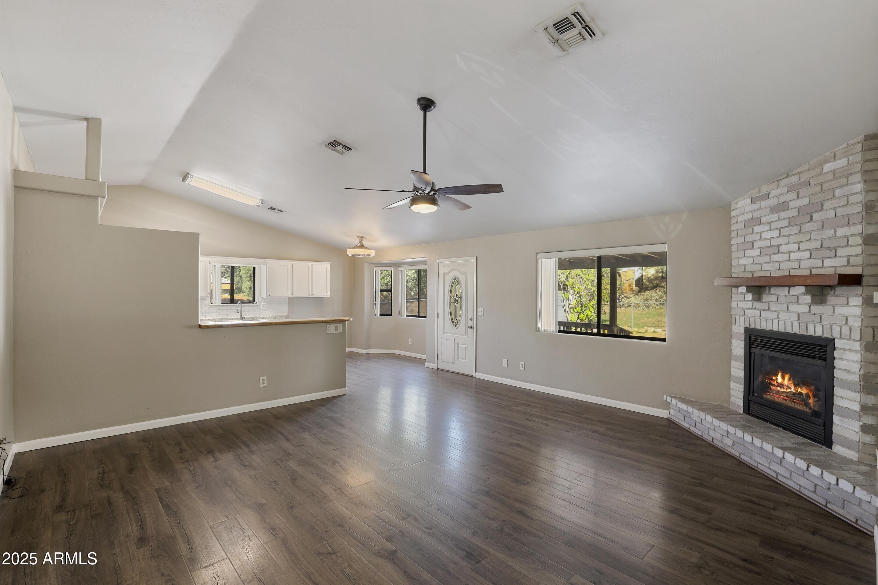 a view of an empty room with wooden floor fireplace and a window