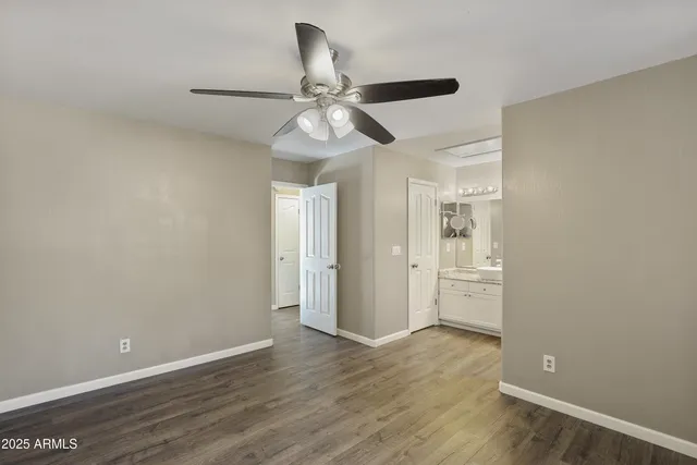 an empty room with wooden floor fan and windows
