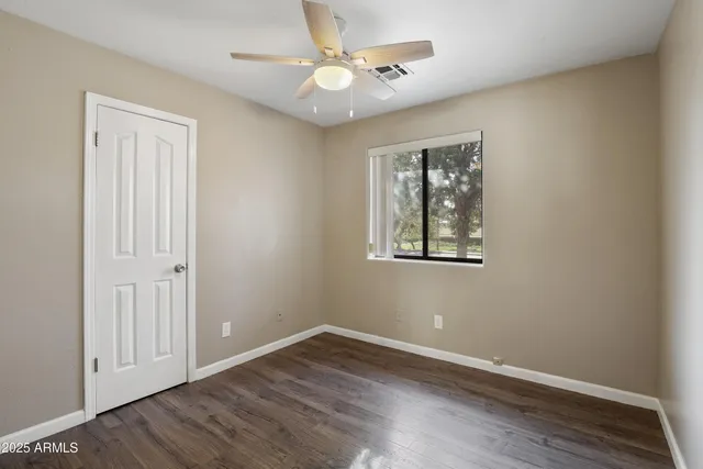 a view of an empty room with window and wooden floor