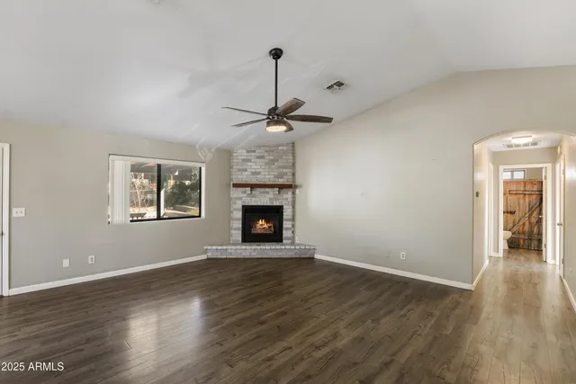 a view of an empty room with wooden floor fireplace and a window