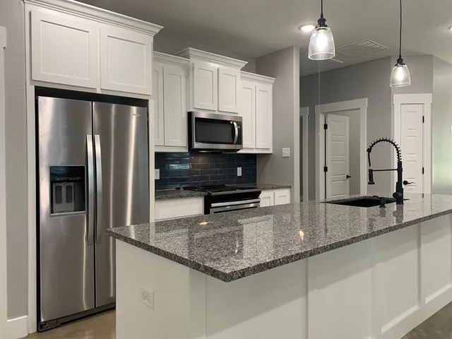 a kitchen with granite countertop a refrigerator and a sink