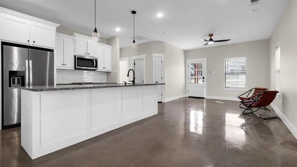 a kitchen with stainless steel appliances granite countertop a refrigerator a stove a sink dishwasher and white cabinets with wooden floor