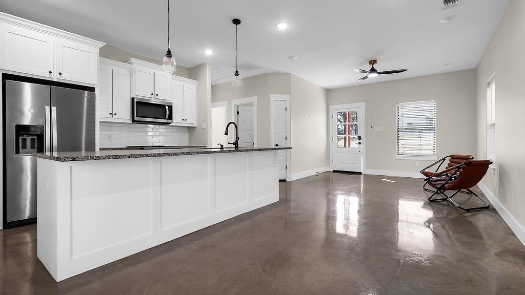727 East Gandy Street Denison, TX 75021 - Photo 4 of 21 a kitchen with stainless steel appliances granite countertop a refrigerator a stove a sink dishwasher and white cabinets with wooden floor