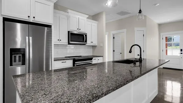 a kitchen with granite countertop a sink stainless steel appliances and white cabinets