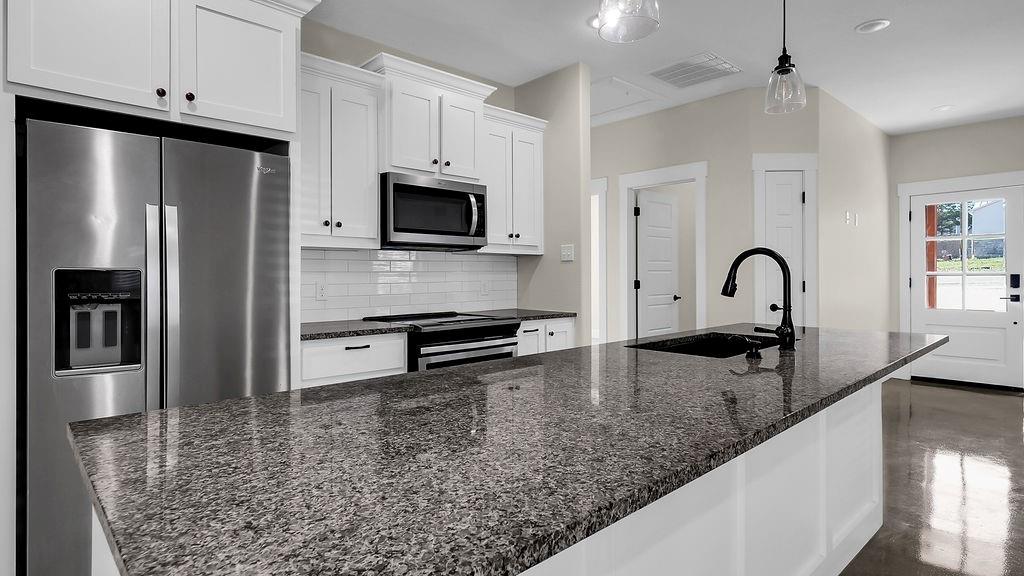 727 East Gandy Street Denison, TX 75021 - Photo 5 of 21 a kitchen with granite countertop a sink stainless steel appliances and white cabinets