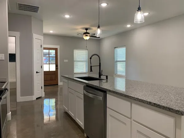 a kitchen with granite countertop white cabinets stainless steel appliances and a wooden floor