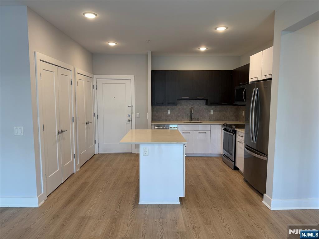 a large kitchen with stainless steel appliances a refrigerator and a sink