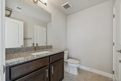 a bathroom with a granite countertop sink a toilet and a mirror