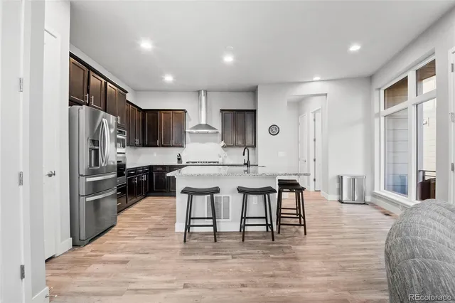 a large kitchen with cabinets chairs and refrigerator
