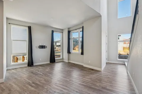 a view of an empty room with window and wooden floor
