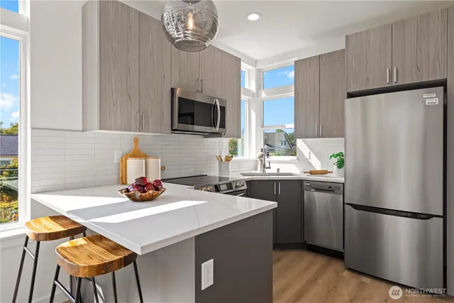 a kitchen with stainless steel appliances a dining table a microwave a refrigerator and cabinets