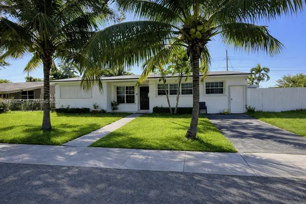 a front view of a house with a garden and palm tree