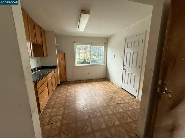 a view of a kitchen in an empty room and a window